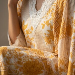 Close-up detail of white lace trim on the V-neckline and mustard yellow printed cotton fabric
