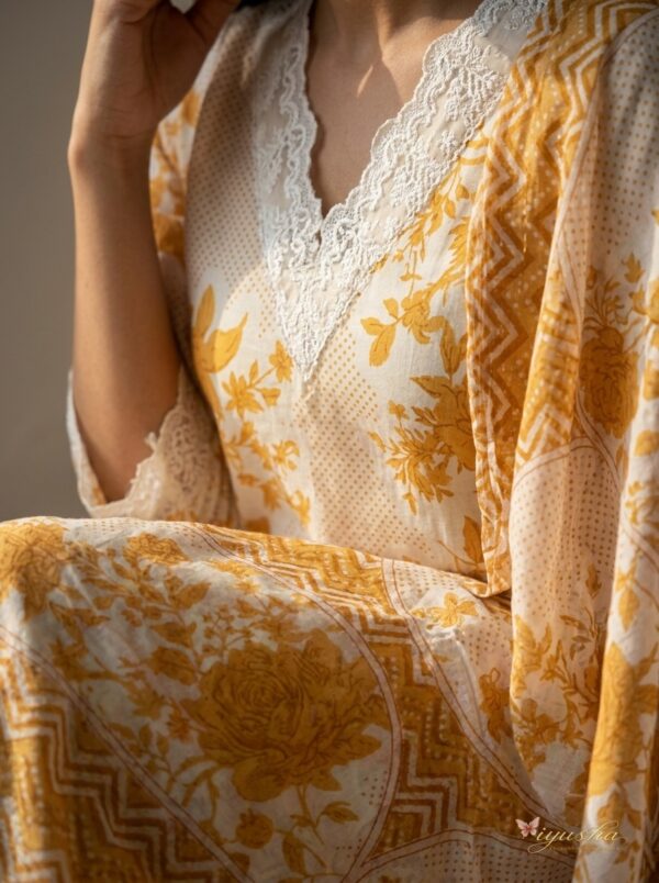 Lace Detail Close Up Close-up detail of white lace trim on the V-neckline and mustard yellow printed cotton fabric