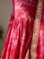 Close-up shot of intricate embellishments and embroidery on vibrant Rani pink fabric.