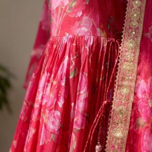 Close-up shot of intricate embellishments and embroidery on vibrant Rani pink fabric.